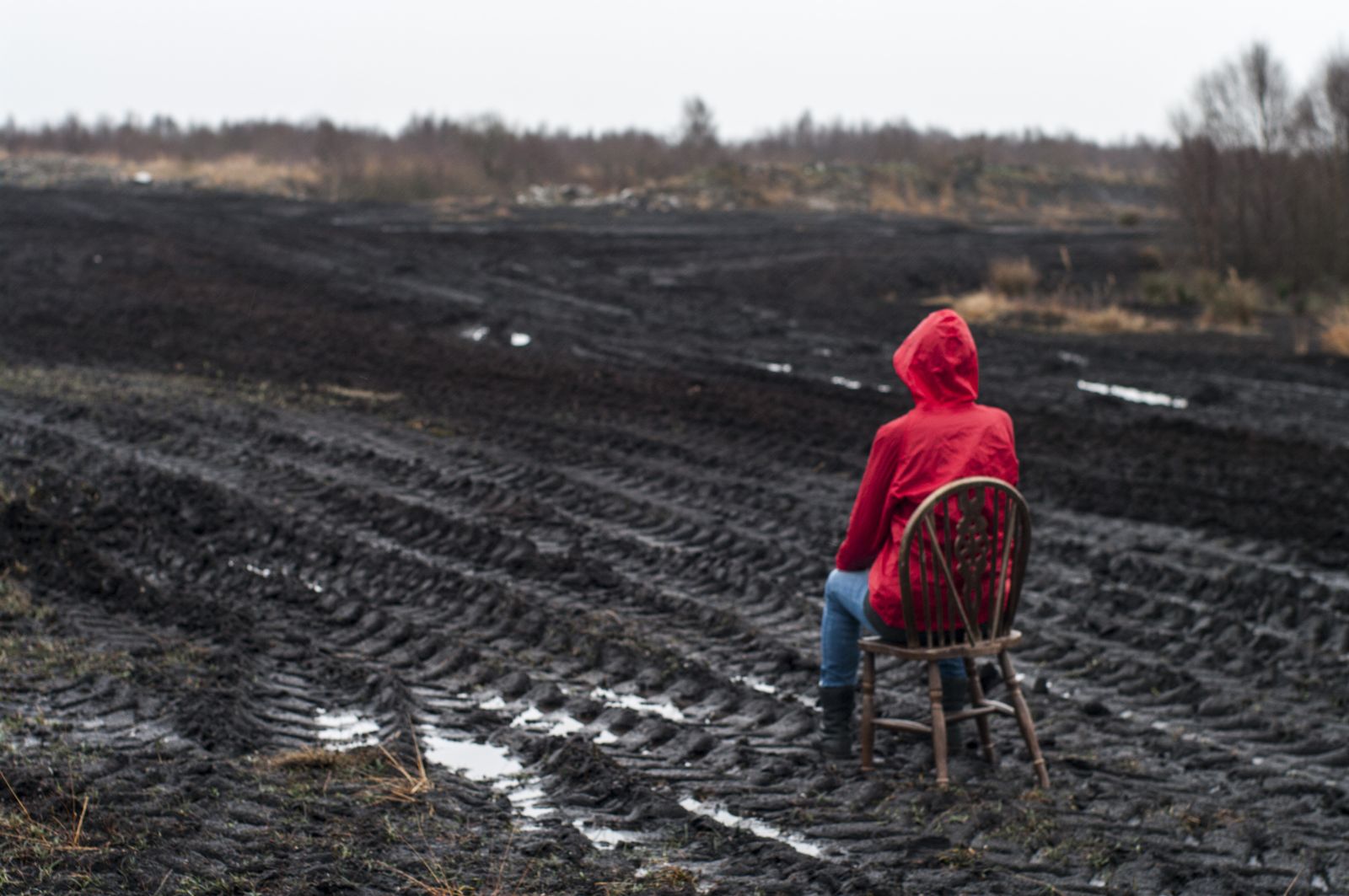 The figure sits in a cut-over peat field striped with tyre tracks
